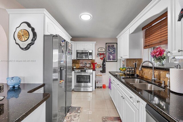 kitchen with backsplash, white cabinets, sink, light tile floors, and appliances with stainless steel finishes