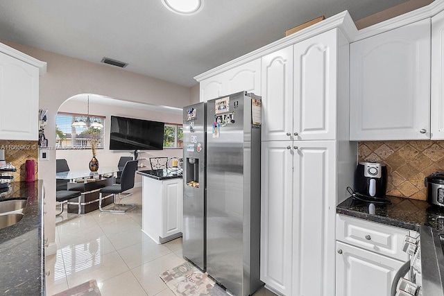 kitchen featuring stainless steel refrigerator with ice dispenser, white cabinets, backsplash, and pendant lighting