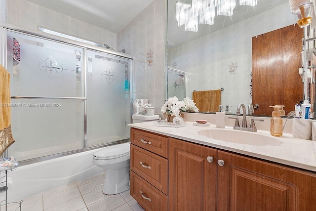 full bathroom with combined bath / shower with glass door, tile walls, tile floors, toilet, and vanity