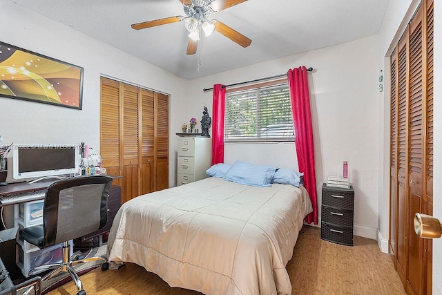 bedroom featuring ceiling fan, hardwood / wood-style flooring, and multiple closets