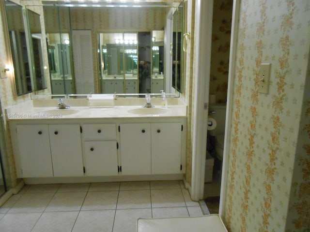 bathroom with toilet, wallpapered walls, a sink, and tile patterned floors