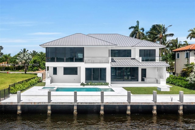 back of property featuring a fenced in pool, a water view, and a patio