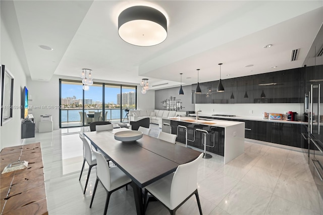 dining room featuring expansive windows, a water view, and sink