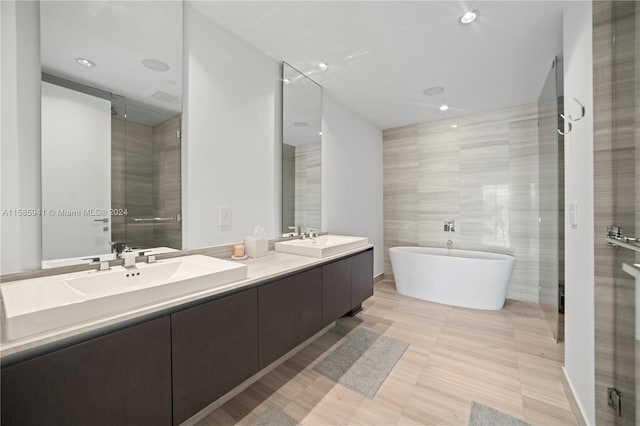 bathroom featuring vanity, separate shower and tub, and tile walls