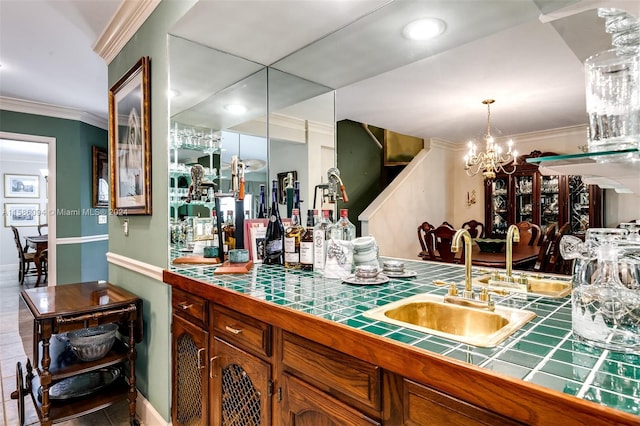 interior space featuring pendant lighting, ornamental molding, sink, tile counters, and a notable chandelier