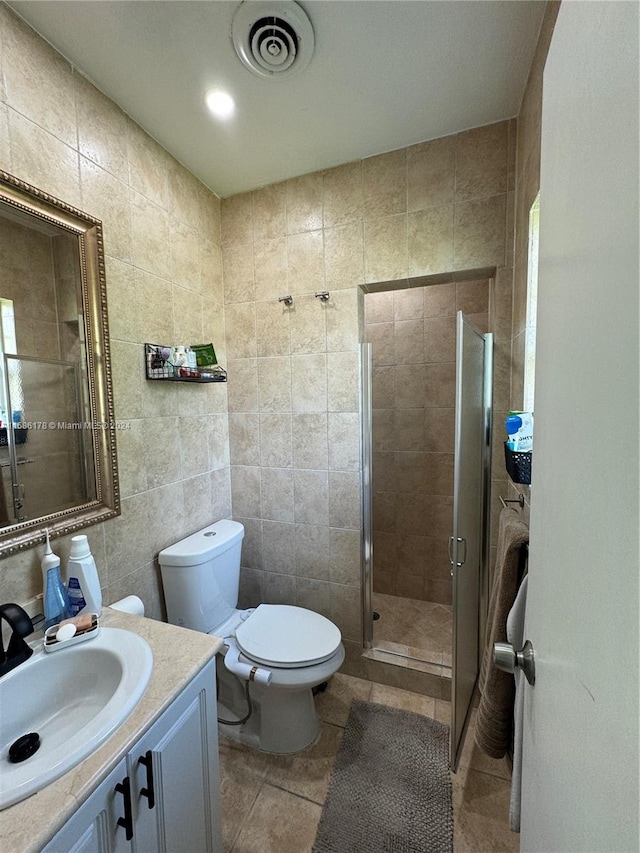 bathroom featuring tile walls, a shower with door, toilet, vanity, and tile floors