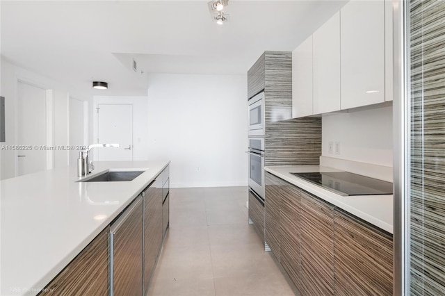 kitchen with tile floors, sink, white cabinets, and stainless steel appliances