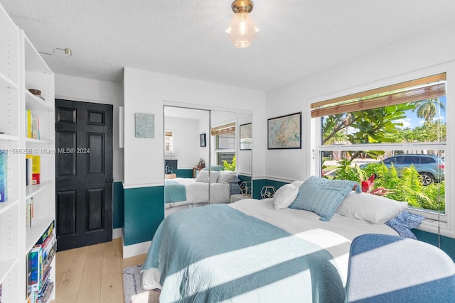 bedroom featuring a closet, a textured ceiling, and light wood-type flooring