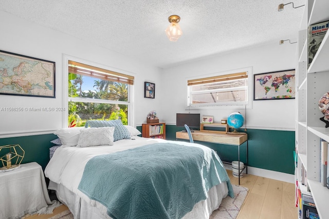 bedroom featuring light hardwood / wood-style floors and a textured ceiling