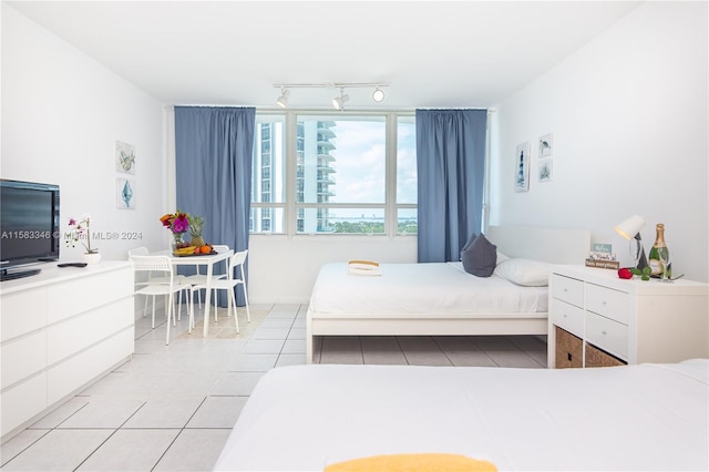 bedroom with rail lighting and light tile floors