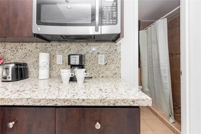 kitchen with light stone countertops, dark brown cabinets, and light tile floors