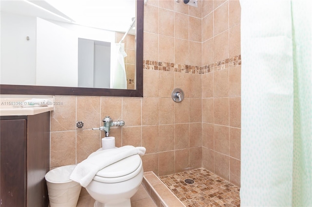 bathroom with tile walls, a tile shower, vanity, and toilet