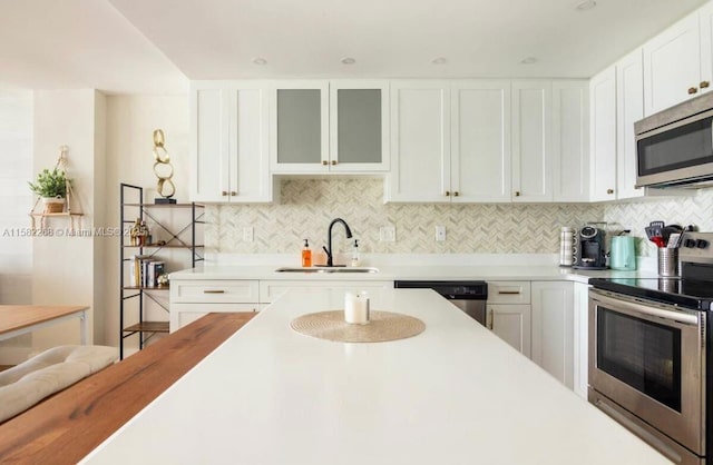 kitchen with tasteful backsplash, white cabinetry, sink, and appliances with stainless steel finishes