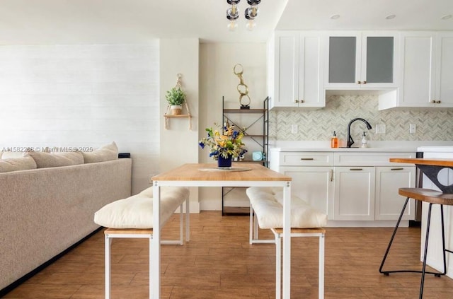 kitchen with white cabinets, light hardwood / wood-style floors, sink, and backsplash