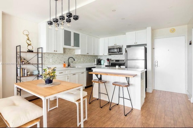 kitchen with white cabinets, decorative backsplash, sink, and stainless steel appliances