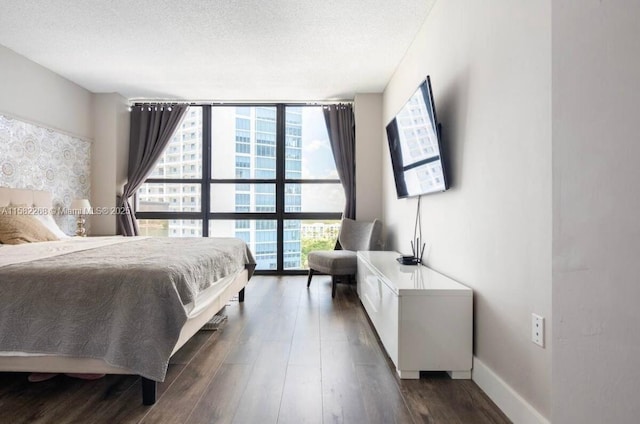 bedroom featuring dark hardwood / wood-style flooring, a textured ceiling, and a wall of windows