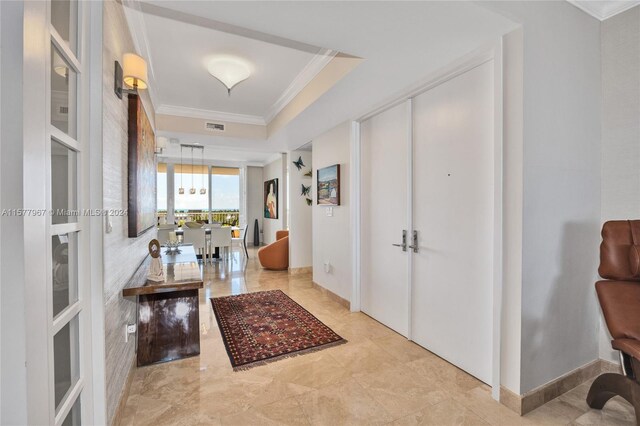 entrance foyer with a tray ceiling, light tile patterned floors, and crown molding