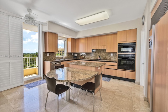 kitchen featuring black appliances, tasteful backsplash, light stone countertops, a kitchen island, and light tile patterned floors