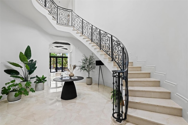 stairway with a towering ceiling and tile floors