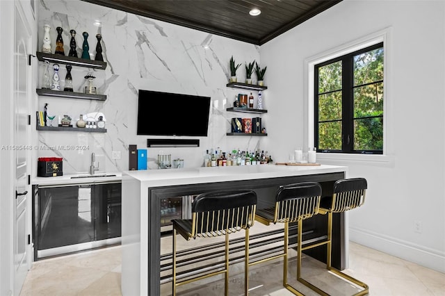 bar with crown molding, sink, and light tile floors