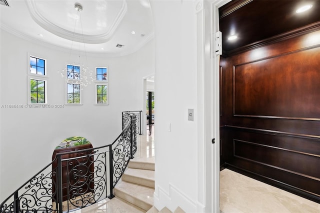 staircase featuring ornamental molding, light tile floors, and a raised ceiling