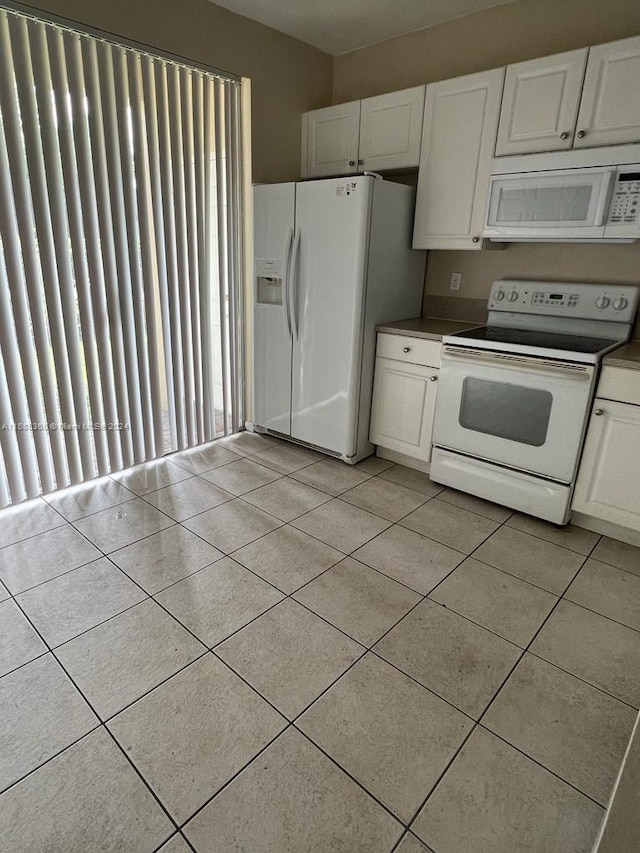 kitchen featuring light tile patterned floors, white appliances, dark countertops, and white cabinetry