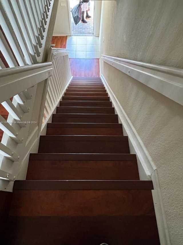 staircase featuring a textured wall and wood finished floors