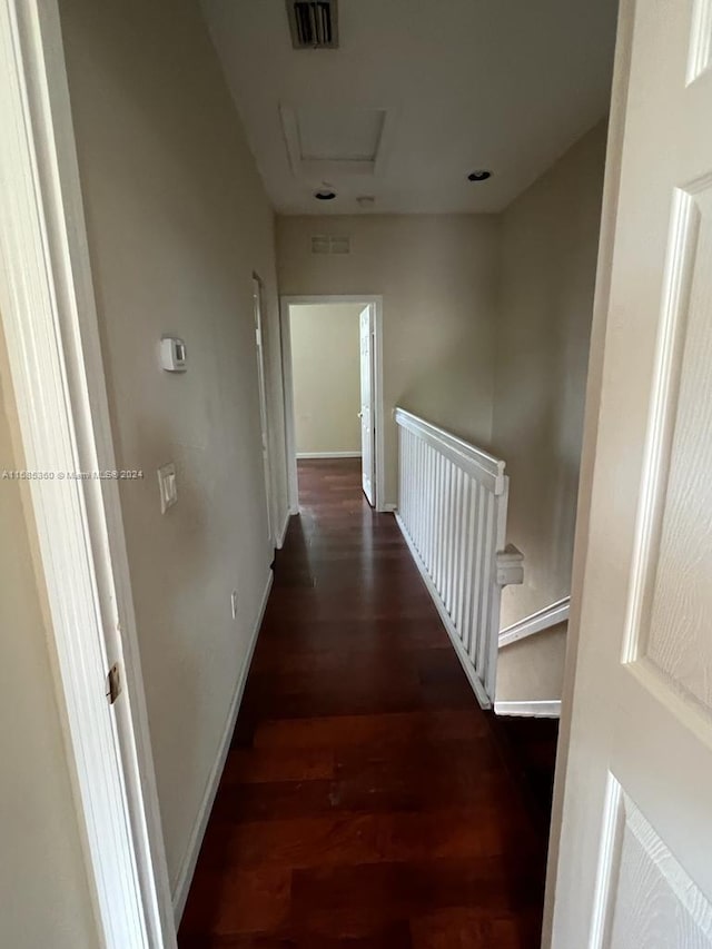 hall featuring attic access, visible vents, baseboards, and wood finished floors