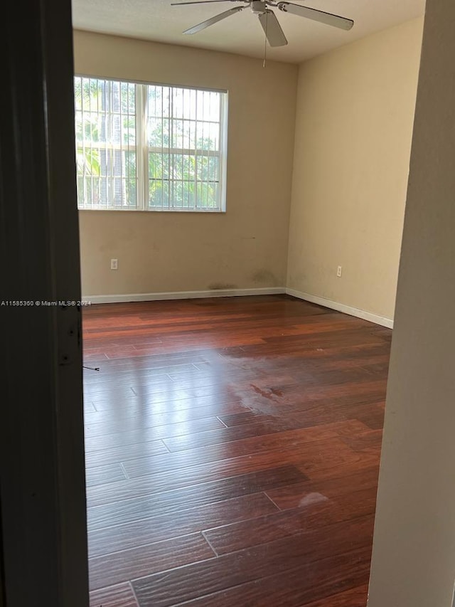 unfurnished room featuring wood finished floors, a ceiling fan, and baseboards