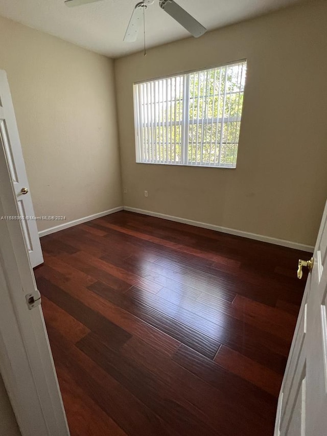 spare room featuring a ceiling fan, baseboards, and wood finished floors