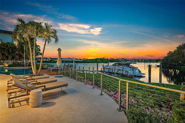 patio terrace at dusk featuring a water view and a boat dock