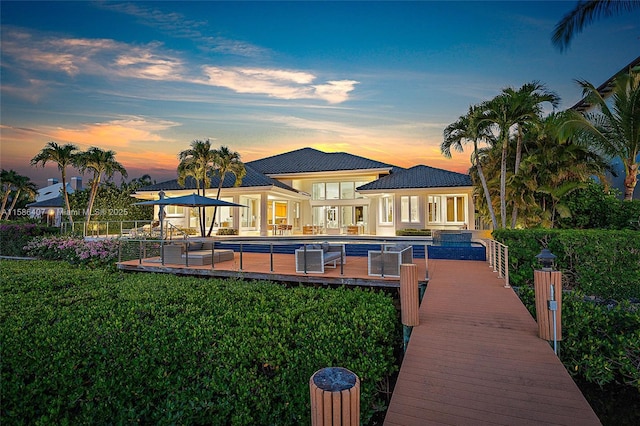 back house at dusk featuring a pool, a yard, and a patio