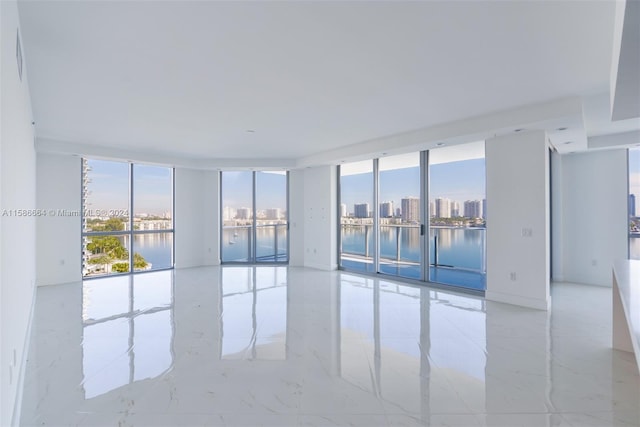 empty room with a water view, expansive windows, and light tile flooring