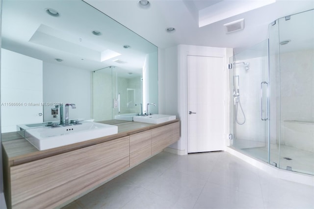 bathroom featuring vanity with extensive cabinet space, double sink, tile floors, and a shower with door