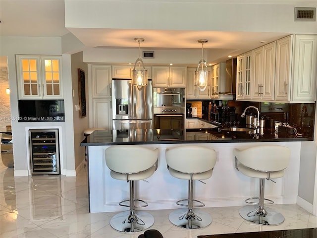 kitchen with cream cabinets, kitchen peninsula, stainless steel appliances, sink, and pendant lighting