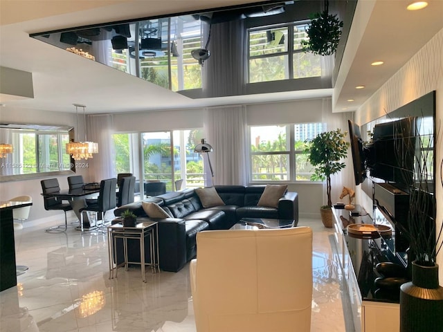 living room with a towering ceiling, a healthy amount of sunlight, light tile flooring, and a chandelier