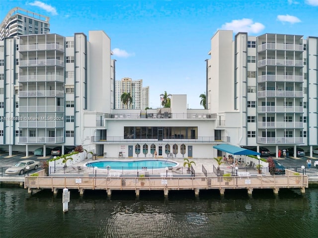 rear view of property with a water view, a patio area, and a balcony