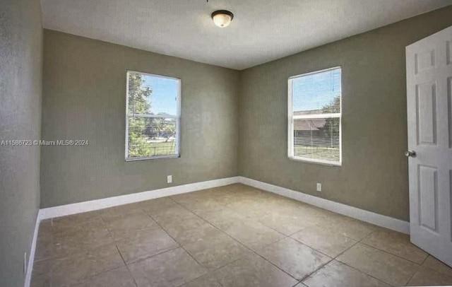 empty room featuring a healthy amount of sunlight and tile flooring