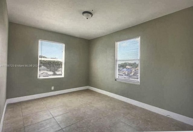 tiled spare room featuring a wealth of natural light