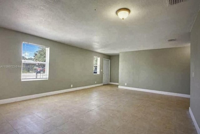 spare room with tile flooring and a textured ceiling