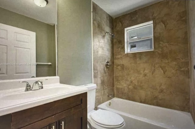 full bathroom featuring tiled shower / bath, vanity, and toilet