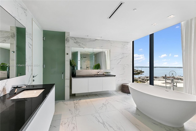 bathroom featuring tile flooring, a water view, a bath to relax in, tile walls, and large vanity