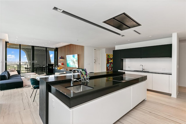 kitchen featuring a center island with sink, white cabinets, expansive windows, and sink