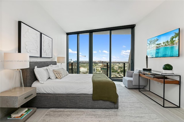 bedroom with a wall of windows and wood-type flooring