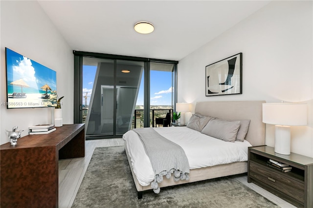 bedroom with floor to ceiling windows, hardwood / wood-style flooring, and access to outside