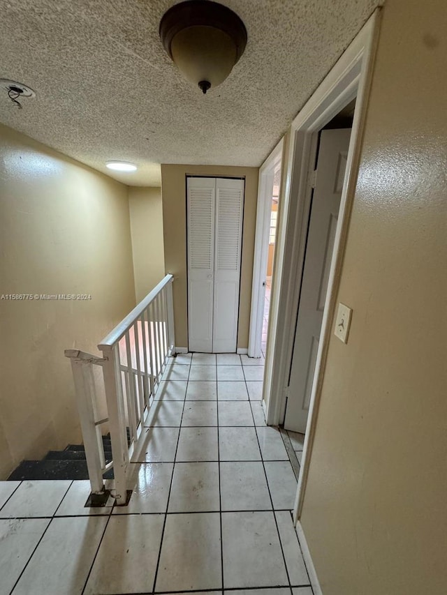 hall featuring light tile patterned flooring and a textured ceiling