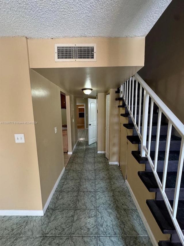 hall featuring a textured ceiling