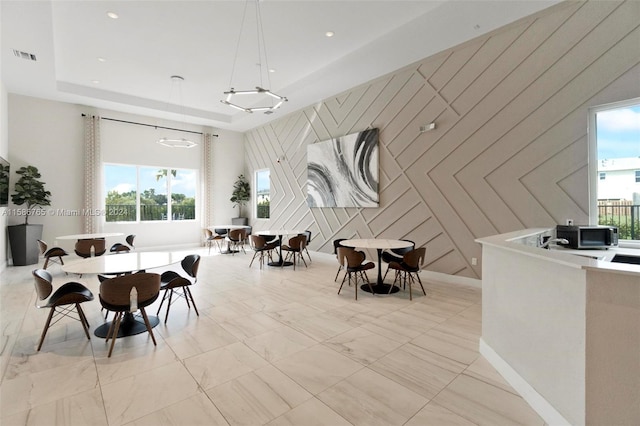 dining room with wooden walls and a raised ceiling