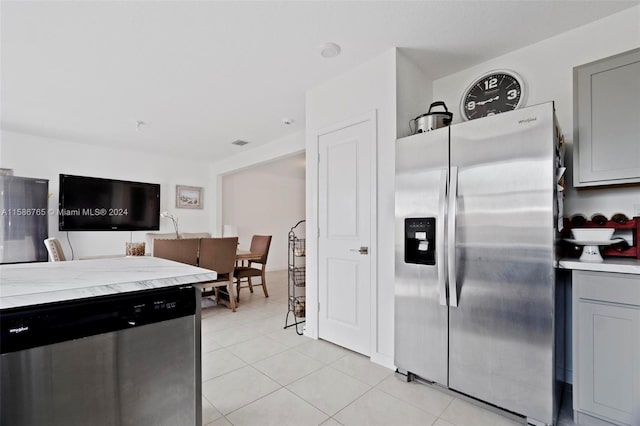 kitchen featuring light tile patterned flooring, gray cabinets, and appliances with stainless steel finishes