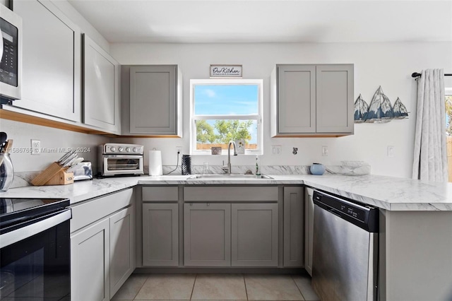 kitchen with appliances with stainless steel finishes, gray cabinetry, and sink